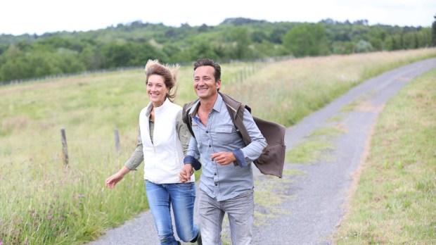 Cheerful couple of farmers running in countryside