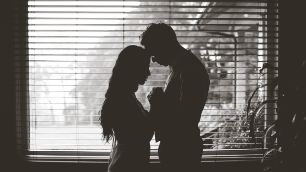 Silhouette of couple praying by a window