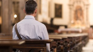 Homme seul, de dos, dans une église.