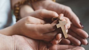 WEB3-CHILD-ADULT-HANDS-CROSS-ROSARY-PRAY-Shutterstock