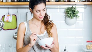 JEUNE FEMME QUI MANGE DANS UN BOL