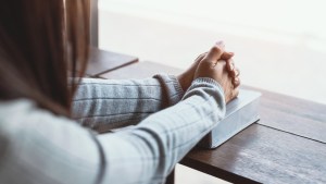 JEUNE FEMME PRIANT AVEC SA BIBLE