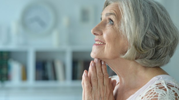 ELDERLY WOMAN PRAYS,