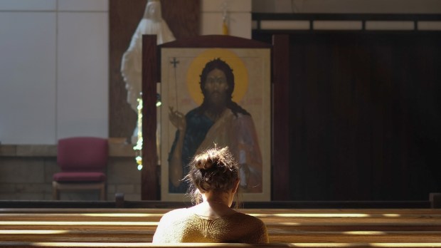 kobieta samotnie modli się w kościele