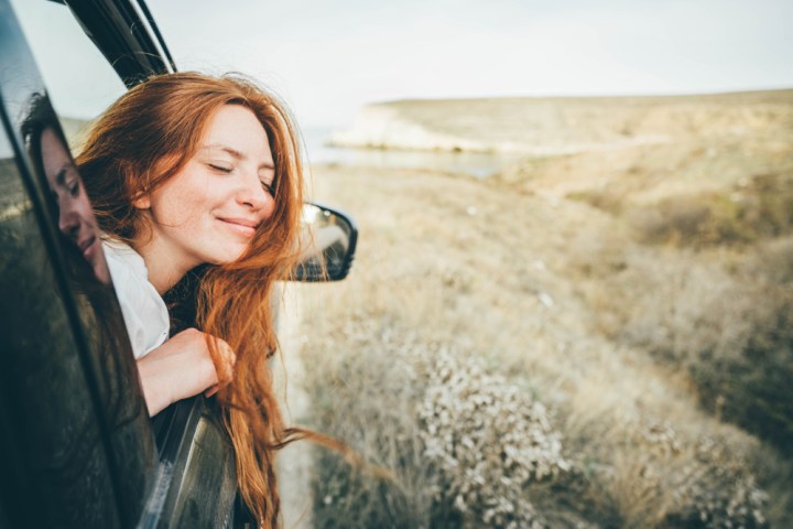 szczęśliwa młoda dziewczyna wygląda z okna samochodu