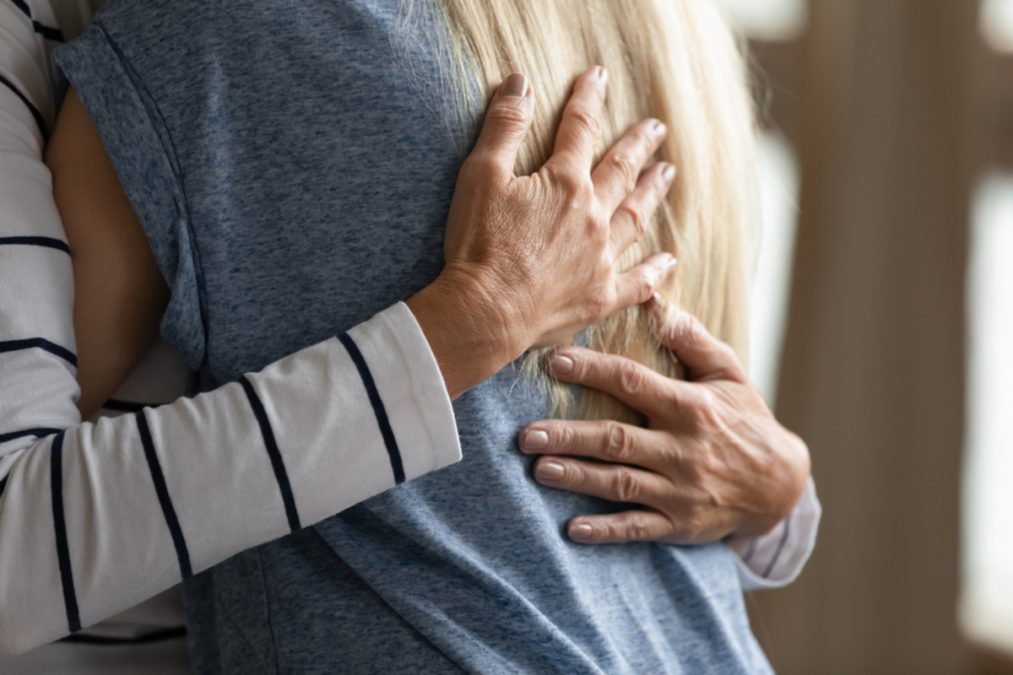 elderly woman hugs younger relative girl