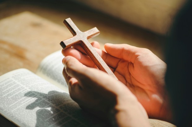 man hands praying to god with the bible and cross
