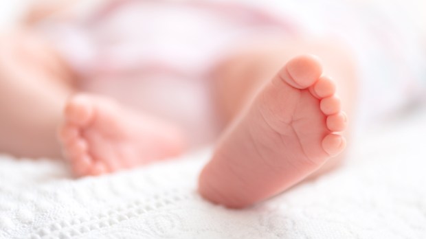 Newborn baby on a white blanket - tiny baby feet closeup