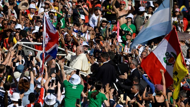 Pilgrims cheer and wave flags as Pope Francis arrives for the welcoming ceremony of World Youth Day