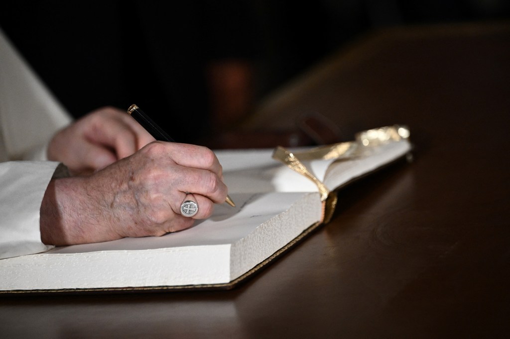 Pope Francis signs a guestbook at the National Palace in Belem, Lisbon