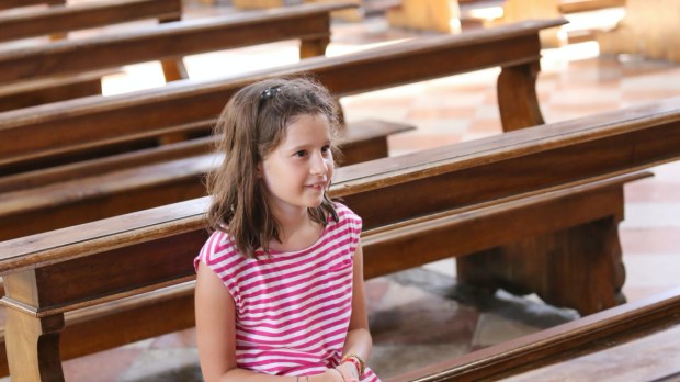 pretty little girl on Pew in the church during a praye